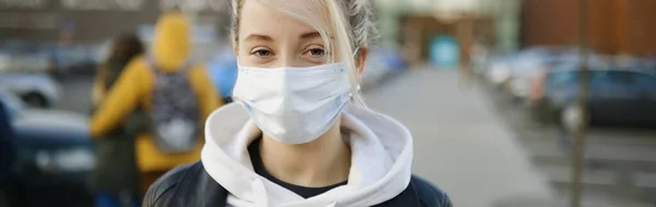 Banner eines blonden Mädchens in medizinischer Maske auf der Straße — Stockfoto