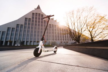 Gün batımında şehir parkında beyaz elektrikli scooter.