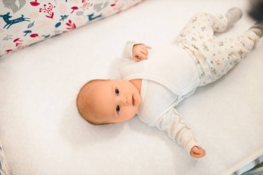 Bebek beşikte yatar ve eve bakar.