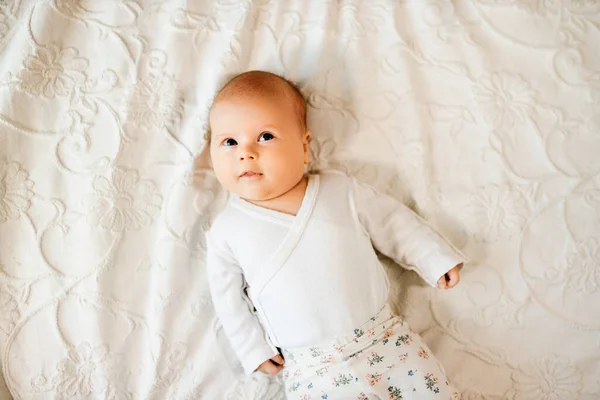 Bebê criança está na cama e sorri em casa — Fotografia de Stock