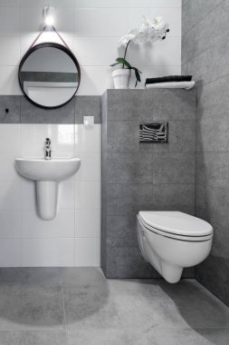 Beyaz duvarlı ve gri kaplamalı banyo iç tasarımı.