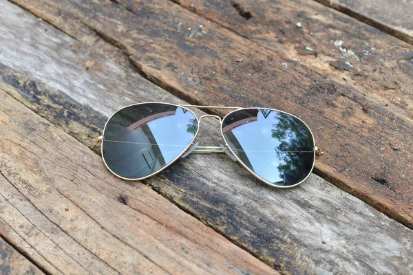 Czarne okulary przeciwsłoneczne na białym tle na tle drewna — Zdjęcie stockowe