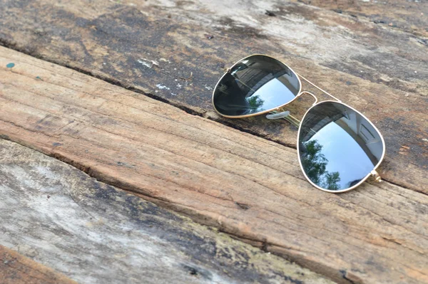 Czarne okulary przeciwsłoneczne na białym tle na tle drewna — Zdjęcie stockowe