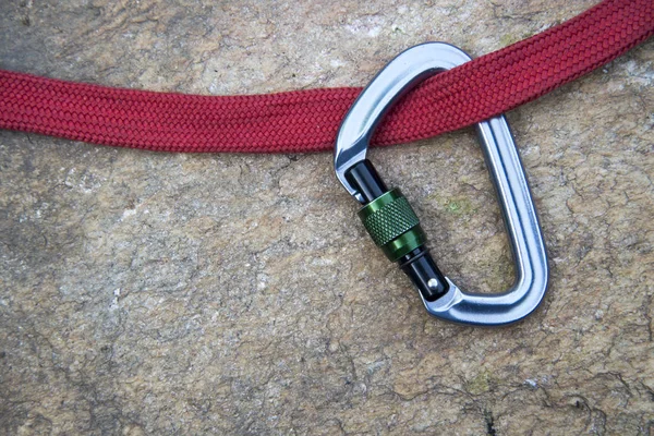 Imagen de un mosquetón y una cuerda roja sobre fondo rocoso —  Fotos de Stock