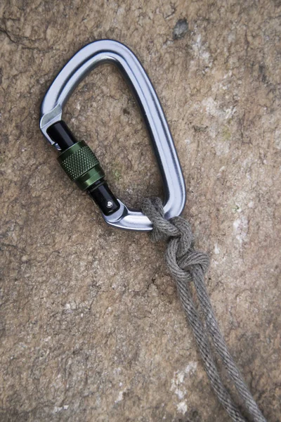 Image of a carabiner hook and rope on rock background — Stock Photo, Image