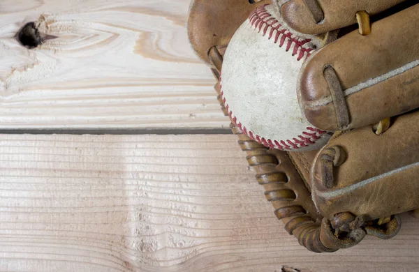 Oude versleten lederen honkbal handschoen en gebruikte bal op een houten tafel — Stockfoto