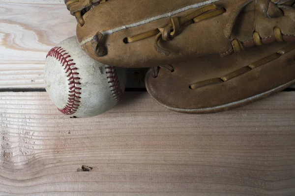 Stare zużyte Skórzane rękawice baseball i używane piłkę na drewnianym stole — Zdjęcie stockowe