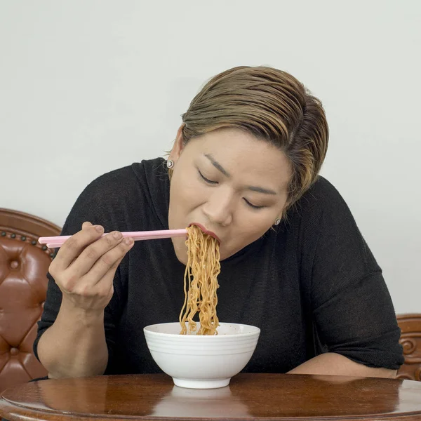 Asian woman eating Asian noodles