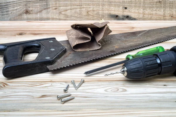 Cacciavite e una vite con la sega e il trapano elettrico su tavolo di legno . — Foto Stock