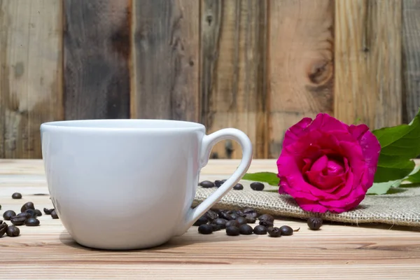 Różowa Róża coffe Puchar i ziarna kawy na drewnianym stole — Zdjęcie stockowe