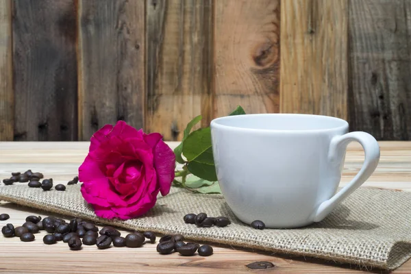 Różowa Róża coffe Puchar i ziarna kawy na drewnianym stole — Zdjęcie stockowe