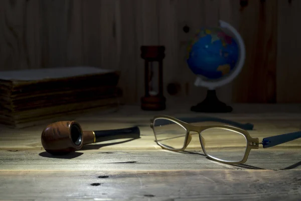 Óculos e cachimbo de tabaco na mesa de madeira . — Fotografia de Stock