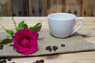 Pembe Gül kahve Kupası ve ahşap masa üzerinde kahve çekirdekleri