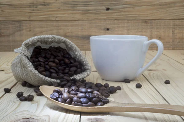 Cup of coffee and coffee beans on wooden table — Stock Photo, Image