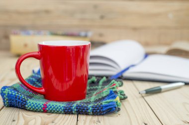 Kırmızı fincan kahve ve kitap günlüğü üzerinde ahşap masa açıldı.