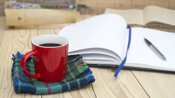 Coupe rouge de café et de livres journal ouvert sur une table en bois . — Photo