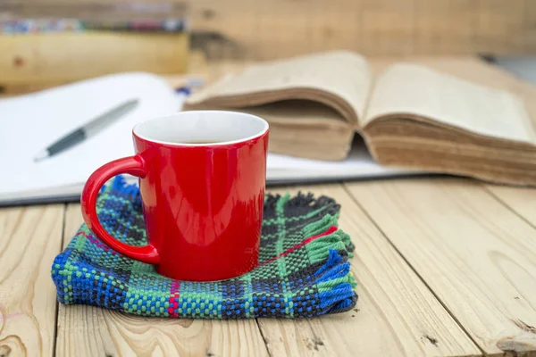 Czerwony kubek kawy i książek otwarty dziennik na drewnianym stole. — Zdjęcie stockowe