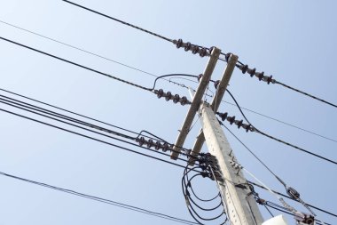Yüksek gerilim elektrik direğine mavi gökyüzü arka planda.
