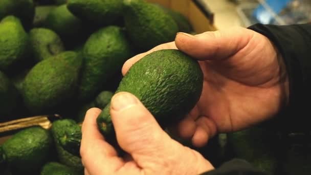 Фермер выбирает авокадо на овощном рынке — стоковое видео