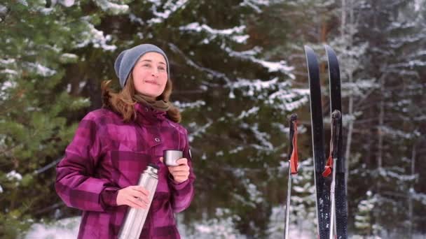Kvinna längdskidåkning drycker från en termos — Stockvideo