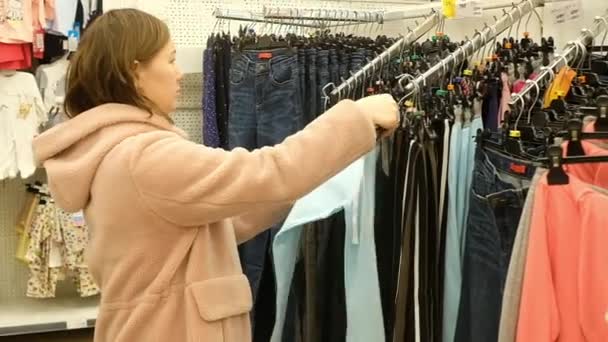 Жінка вибирає одяг на ринку. Шопінг — стокове відео