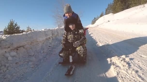 Three children are riding a snow scooter from a mountain. — 비디오