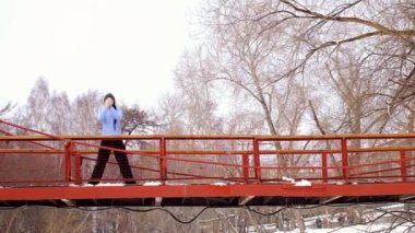 Kışın açık havada yoga jimnastiği yapan genç bir kadın.