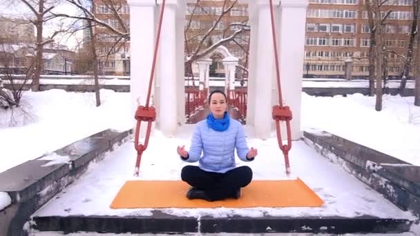 Молода жінка практикує гімнастику йоги взимку на відкритому повітрі — стокове відео