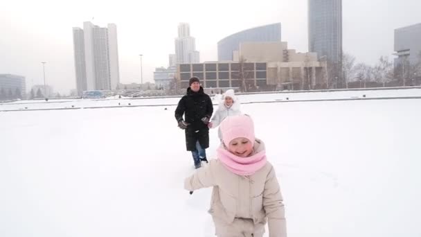 Vater und Mutter laufen mit ihrer kleinen Tochter im Winter in der Stadt. — Stockvideo