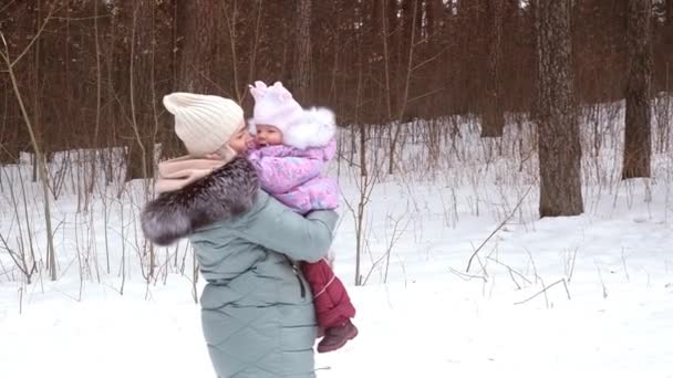 Genç anne kışın bebeğiyle parkta yürür. — Stok video
