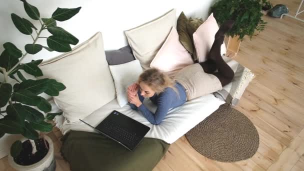 Vacker glad kvinna med glada leende liggande på soffan med laptop — Stockvideo