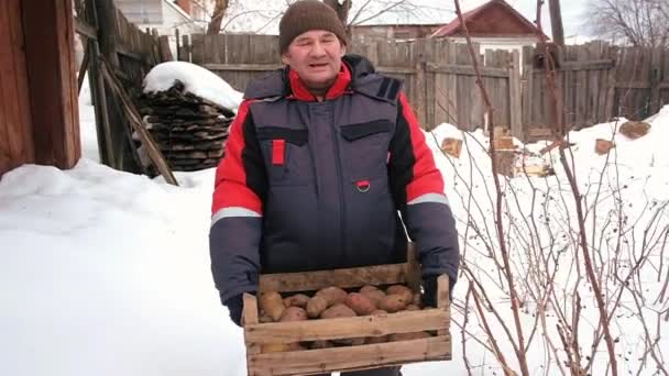 O agricultor carrega uma caixa de batatas. Existências de Inverno — Vídeo de Stock