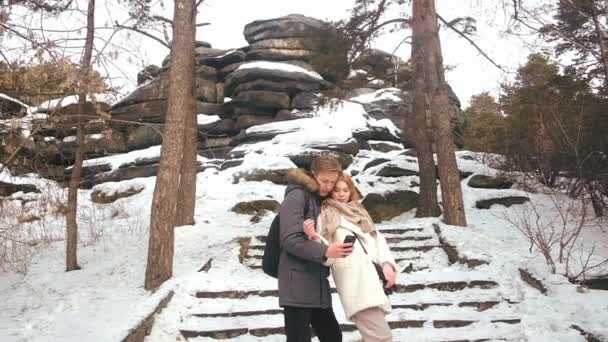 Ett ungt par fotograferas på vintern vid klipporna — Stockvideo