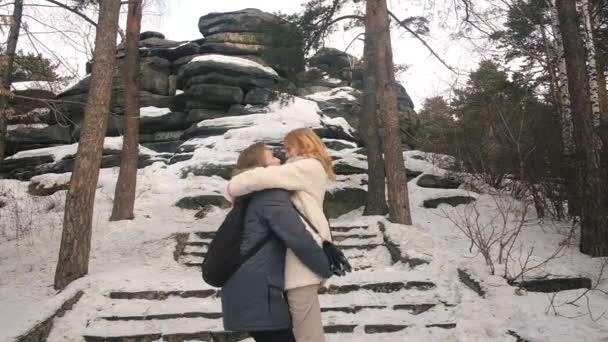 Portrait of happy smiling young couple hugging while walking in snowy winter park . — ストック動画