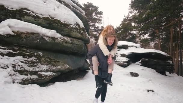 Der Kerl rollt das Mädchen auf den Rücken. Winterspaß. — Stockvideo