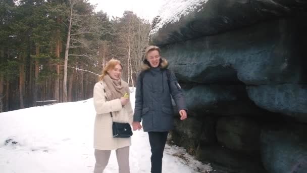 Portrait of happy smiling young couple hugging while walking in snowy winter park . — Wideo stockowe