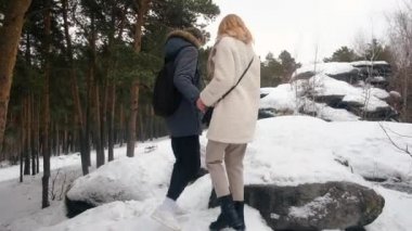 portrait of happy smiling young couple hugging while walking in snowy winter park .