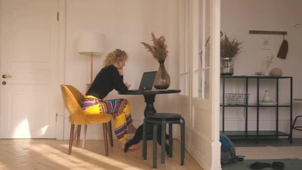 Жінка сидить за комп'ютером вдома . — стокове відео