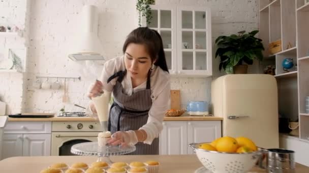 Confectioner woman decorates cupcakes. On the kitchen — Stock Video