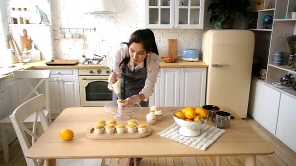 Confectioner kvinna dekorerar muffins. På köket — Stockvideo