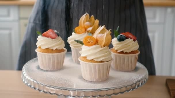 Dessert chefs female hand decorates delicious muffins with icing sugar. — Stock Video