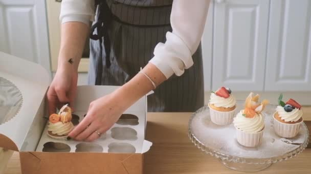 Confeiteiro coloca cupcakes em uma caixa — Vídeo de Stock