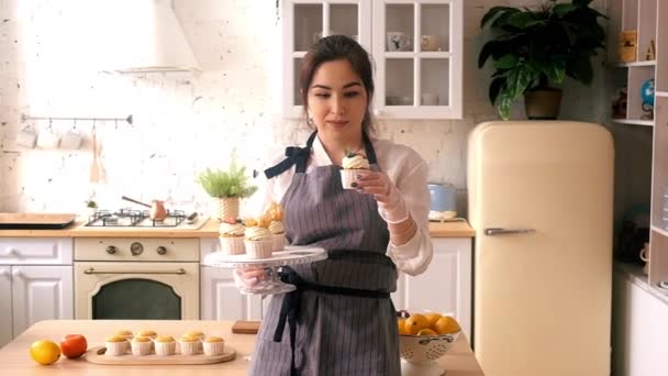 Confectioner woman decorates cupcakes. On the kitchen. — Stock Video