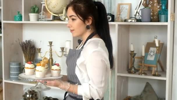 菓子屋の女性はカップケーキを飾る。台所で. — ストック動画