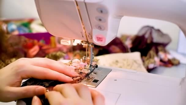 Una mujer cose en una máquina de coser, una máquina de coser de dos agujas, un estudio de costura de moda, una manicura roja en sus manos, tela verde, tela de color lima, primer plano — Vídeos de Stock
