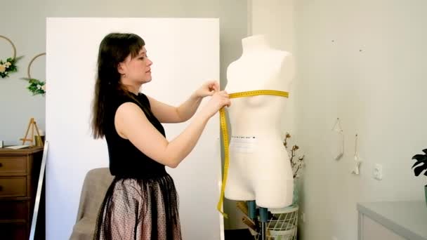 Dressmaker, profesjonalny projektant mody. Mierzy manekina miernikiem. Studio szycia. Widok w połowie długości, kobieta 30-40 lat — Wideo stockowe