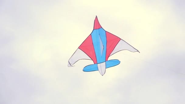 Een kleurige vlieger met een emoji hangt in de lucht tegen een blauwe lucht op een zonnige zomerdag op een city kite festival. Vlieger zwaait in de wind. Kinderen — Stockvideo