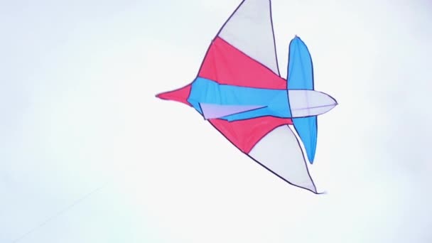 A colored kite with an emoji hangs in the air against a blue sky on a sunny summer day at a city kite festival. kite sways in the wind. Childrens — Stock Video