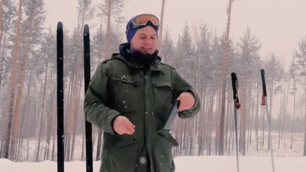 Concepto de viaje - turista toma fotos de dos pares de esquís anchos en la aldea en el día de invierno en el teléfono inteligente, Rusia — Vídeo de stock
