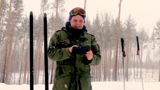 Matkailukonsepti - turisti ottaa kuvan kahdesta parista laajoja suksia kylässä talvipäivänä älypuhelimella, Venäjällä — kuvapankkivideo